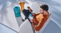 Online-Terminbuchung in Ihrer Mercedes-Werkstatt: Junger Mann in weißem Sessel bucht Online-Werkstatttermin über sein I-Pad.
